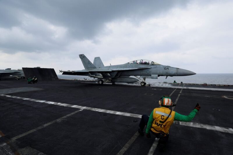 A flight operating crew member signals a F/A-18E Super Hornet fighter jet on the flight deck of the USS Dwight D. Eisenhower (CVN 69) aircraft carrier in Southern Red Sea