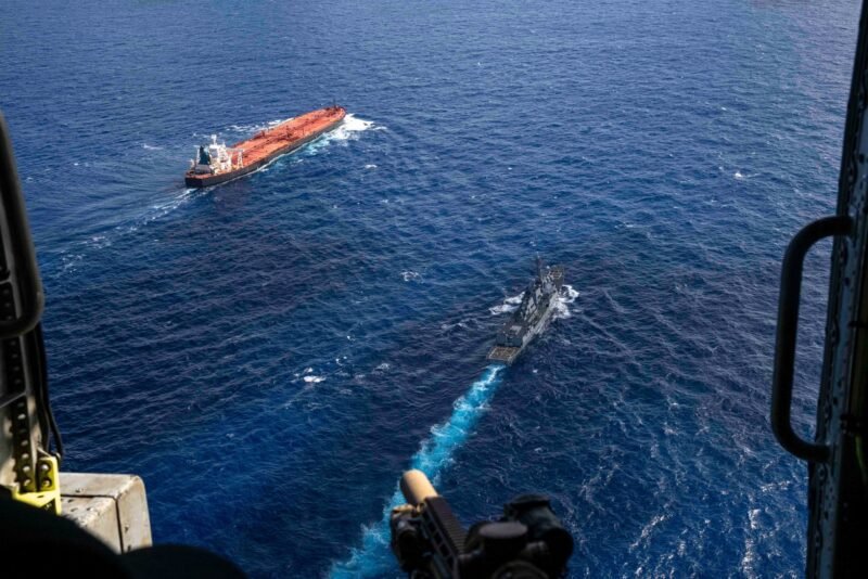 Aerial view of a U.S. Navy warship trailing a large oil tanker during a maritime interdiction in open ocean waters