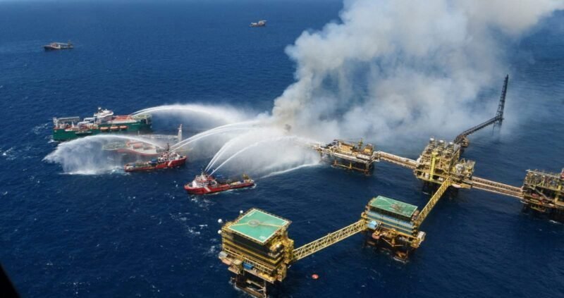 Firefighting vessels spraying water on a burning offshore oil platform at sea