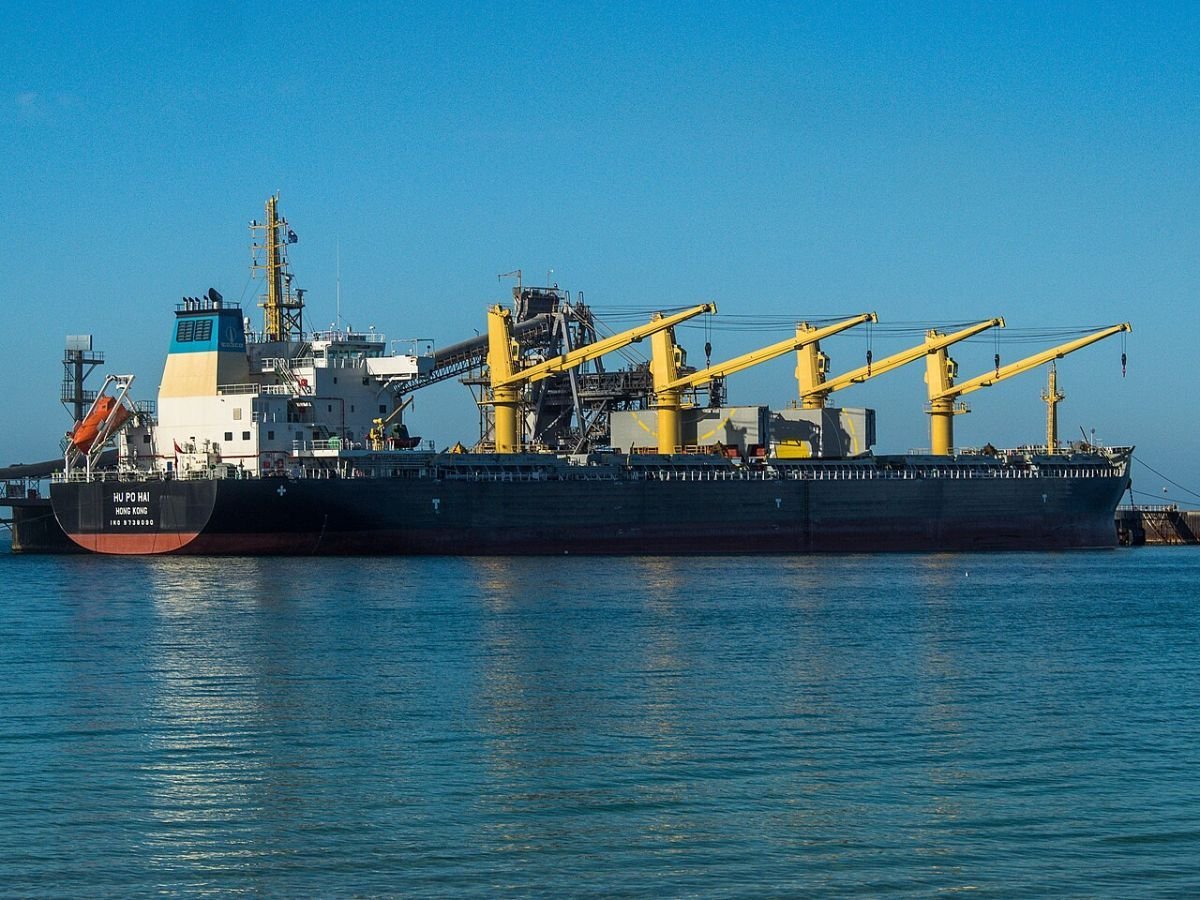 Geared bulk carrier moored alongside a port berth under a clear blue sky