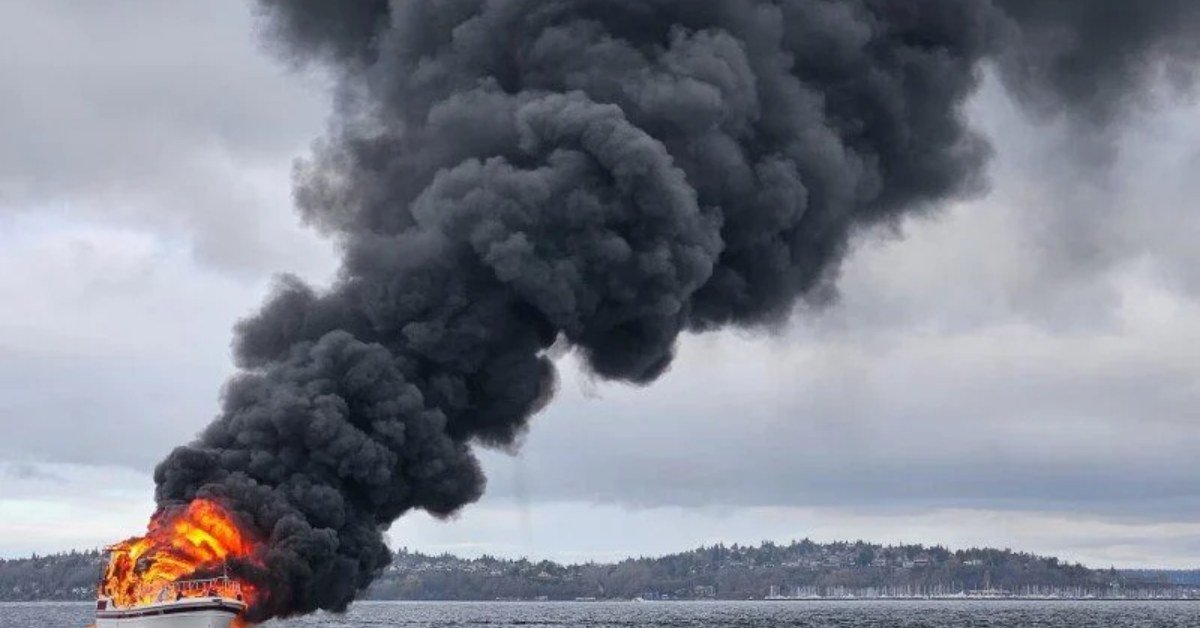 Ship on fire at sea with thick black smoke rising