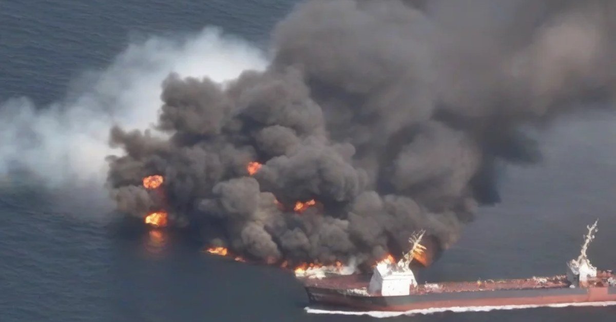 Merchant ship on fire with thick black smoke at sea